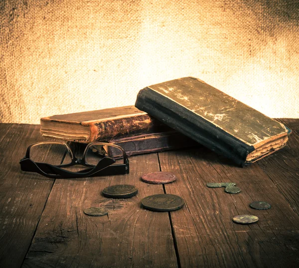 Vintage books and coins and spectacles on old wooden table. Tone — Stock Photo, Image