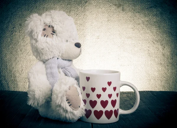 Bear with a cup with hearts on the background of sacking — Stock Photo, Image