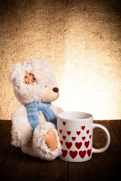 Bär mit einer Tasse mit Herzen auf dem Hintergrund der Säcke — Stockfoto