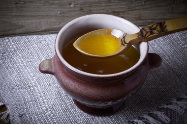 Ghee ve kaşık keten peçete ile toprak kap. Rustik natürmort.