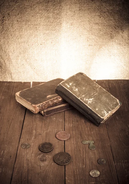 Livres anciens, pièces de monnaie et lunettes sur une vieille table en bois. Ton : — Photo