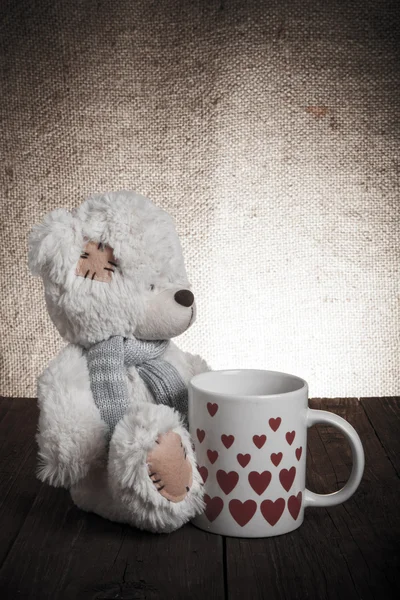 Medvěd s šálkem pytloviny s srdci na pozadí — Stock fotografie