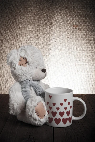 Bär mit einer Tasse mit Herzen auf dem Hintergrund der Säcke — Stockfoto