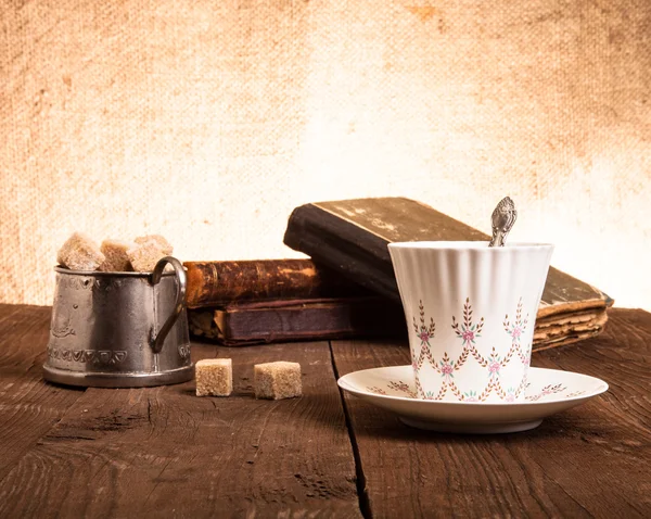Ceașcă de cafea, bol de zahăr și stivă de cărți vechi pe lemnul vechi — Fotografie, imagine de stoc