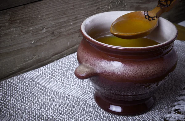 Pot d'argile avec ghee et cuillère sur serviette en lin. Nature morte rustique . — Photo