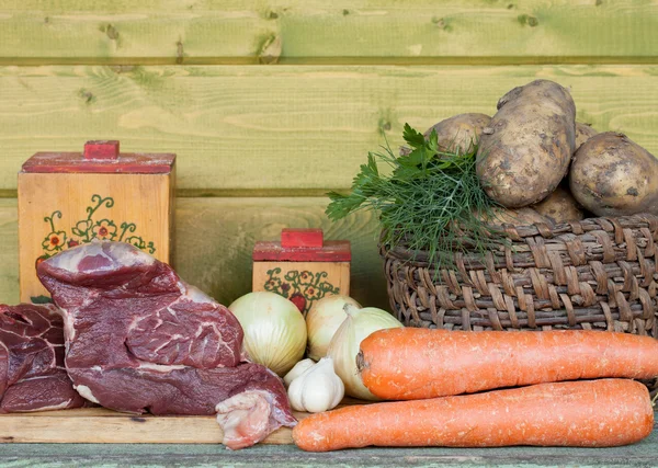 Carne crua, batata, cebola, alho, cenoura e endro na mesa de madeira — Fotografia de Stock