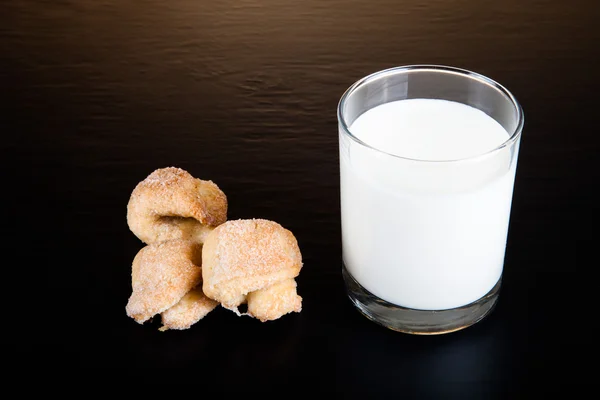 Glass of milk and cookies on a black table — Stock Photo, Image