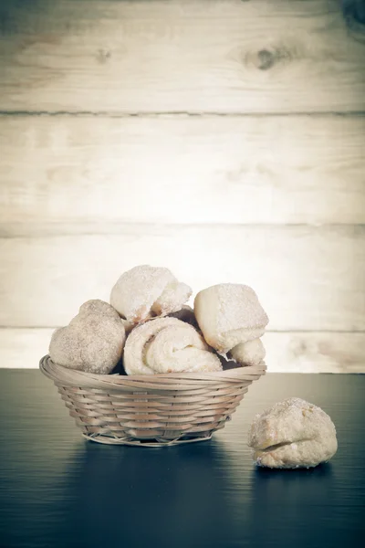 Basket of cookie on a black table against old wooden background. — Stock Photo, Image