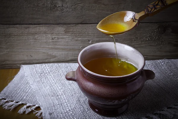 Pot d'argile avec ghee et cuillère sur serviette en lin. Nature morte rustique . — Photo