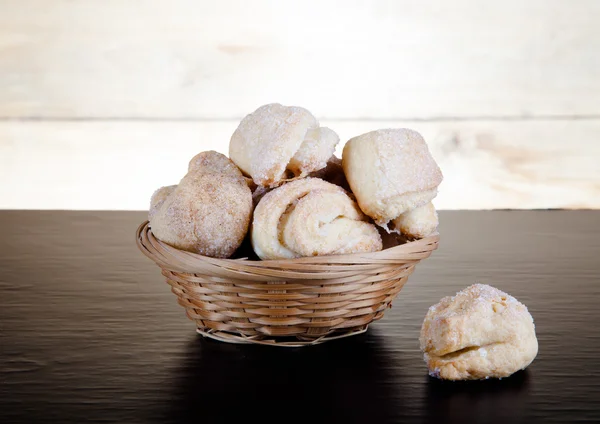 Basket of cookie on a black table against old wooden background — Stock Photo, Image