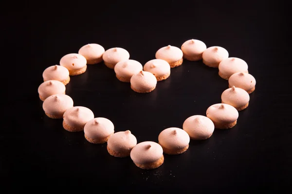 Small cookies laid in the shape of heart on black background. To — Stock Photo, Image