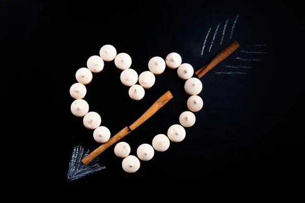 Small cookies laid in the shape of heart with arrow and cinnamon — Stock Photo, Image
