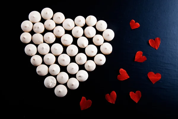 Small cookies laid in the shape of heart with red paper hearts o — Stock Photo, Image