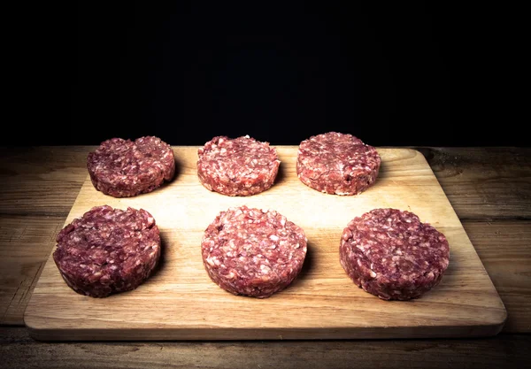 Chuleta cruda de carne picada en una tabla de cortar de madera en bac negro — Foto de Stock