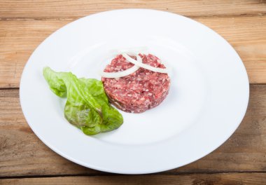 Ham pirzola, soğan ve beyaz bir tabak salata
