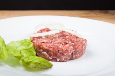 Ham pirzola, soğan ve beyaz bir tabak salata