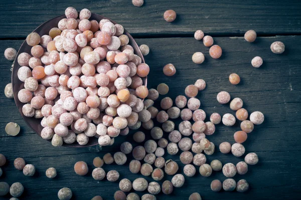 Copper bowl with dried peas on old wooden table. — Stock Photo, Image