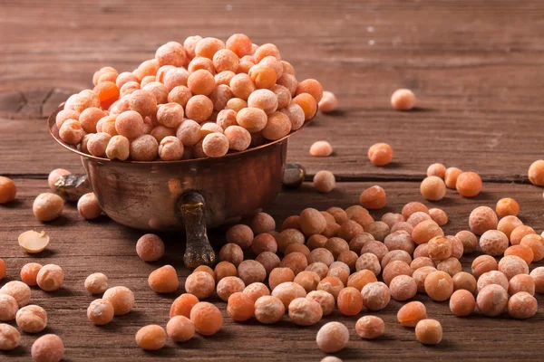 Cuenco de cobre con guisantes secos en mesa de madera vieja . — Foto de Stock