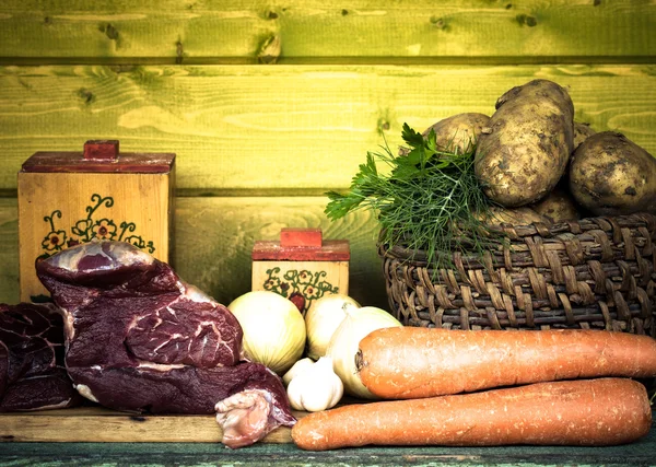 原料肉、 土豆、 洋葱、 大蒜、 胡萝卜、 莳萝木制的桌子上 — 图库照片