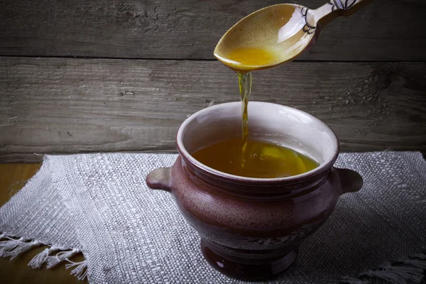 Maceta de barro con ghee y cuchara en servilleta de lino. Naturaleza muerta rústica . — Foto de Stock