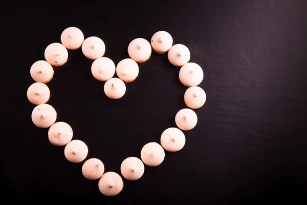 Galletas pequeñas colocadas en forma de corazón sobre fondo negro. Para — Foto de Stock