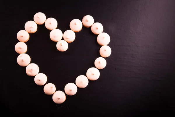 Piccoli biscotti posati a forma di cuore su sfondo nero. Per — Foto Stock
