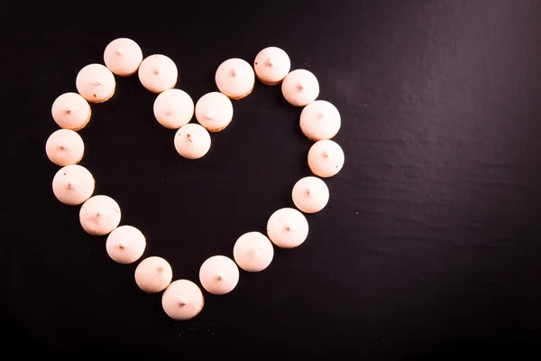 Small cookies laid in the shape of heart on black background. To — Stock Photo, Image