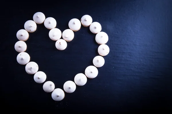 Small cookies laid in the shape of heart on black background. To — Stock Photo, Image