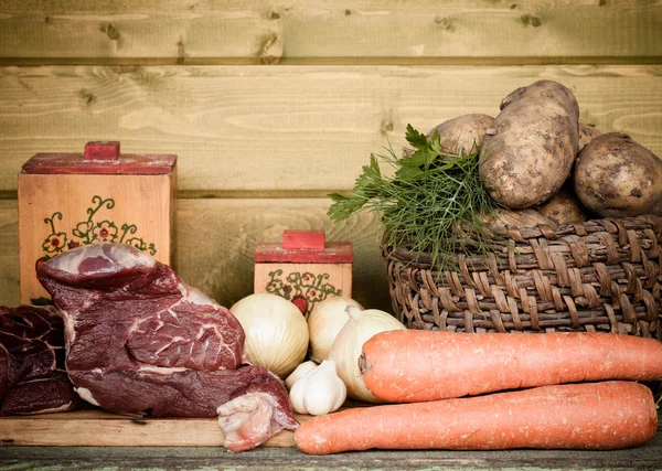 Carne crua, batata, cebola, alho, cenoura e endro na mesa de madeira — Fotografia de Stock