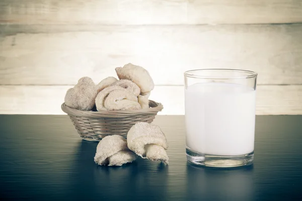 Basket of cookie and glass of milk on a black table against old — Stock Photo, Image