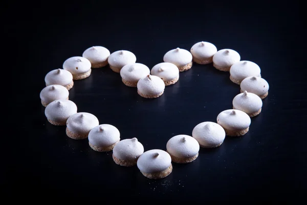 Small cookies laid in the shape of heart on black background. To — Stock Photo, Image