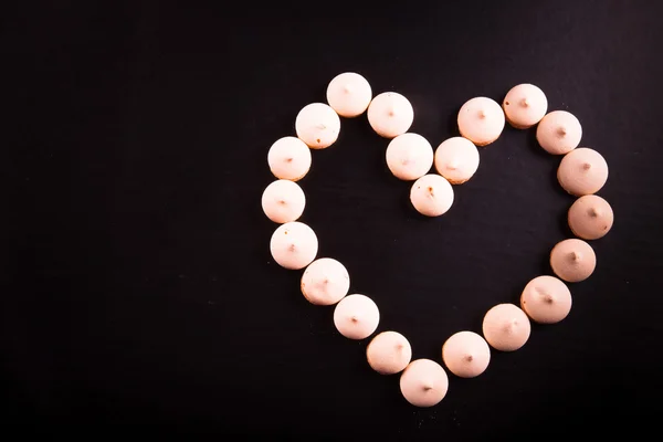 Galletas pequeñas colocadas en forma de corazón sobre fondo negro. Para — Foto de Stock