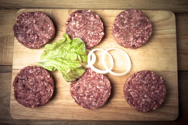 Ruwe kotelet van gehakt vlees met blad van salade en ringen van UI — Stockfoto