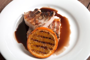 Beyaz tabakta portakal soslu ızgara et