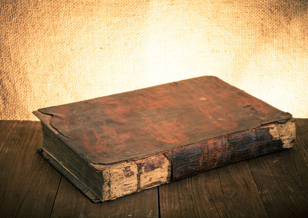 Ancient book on the old wooden table. Toned