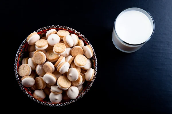 Small cookies in the Turkish bowl and glass of milk on a black t — Stock Photo, Image