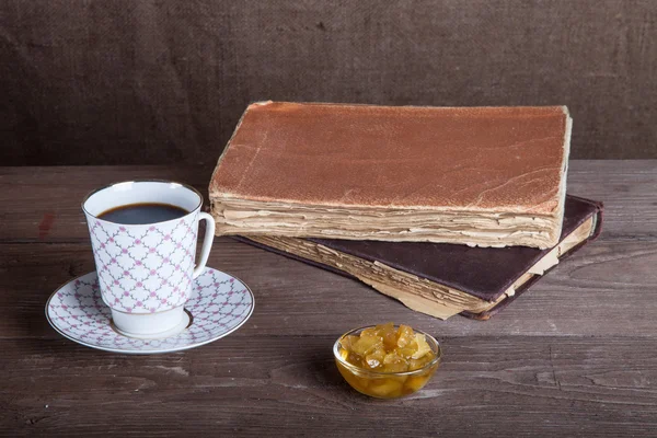 Eine Tasse Kaffee, Marmelade und alte Bücher auf einem Holztisch — Stockfoto