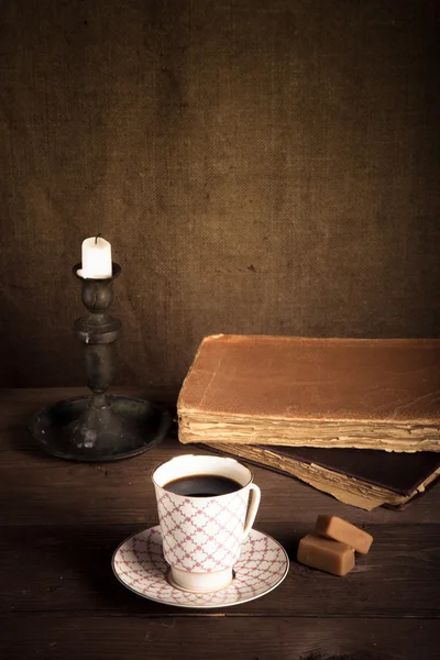 Стек старих книг, чашка кави, цукерки та свічки на старому w — стокове фото