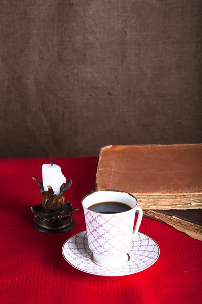 Stack di vecchi libri, tazza di caffè, e candela antica sul rosso — Foto Stock