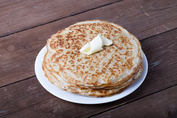 Empilement de crêpes russes - blini sur une assiette de wite sur du vieux bois — Photo