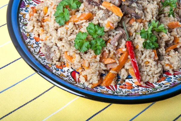 Hot delicious pilaf on a turkish plate on yellow striped tablecl — Stock Photo, Image