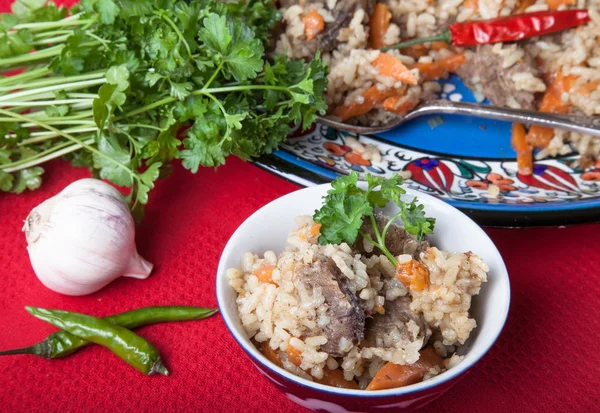 Hot delicious pilaf with garlic, hot pepper and parsley on red t — Stock Photo, Image