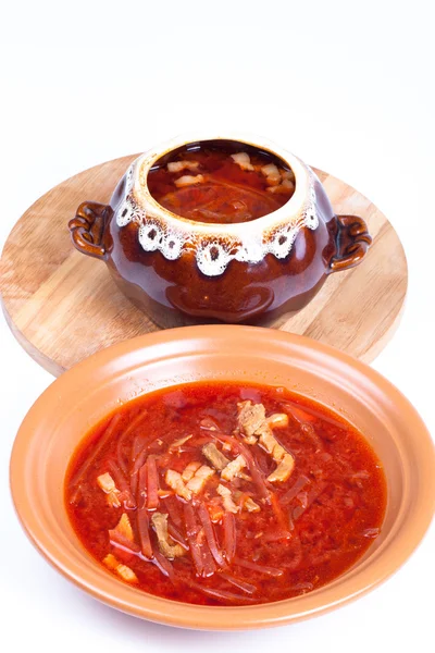 Soupe de bortsch russe dans un bol et une casserole sur un fond clair — Photo