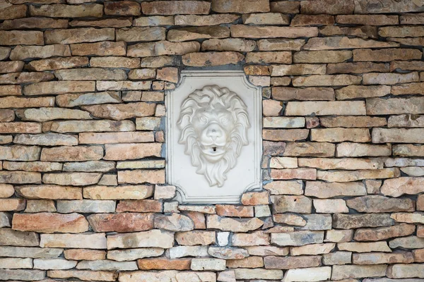Wall of natural stones with bas-relief of lion