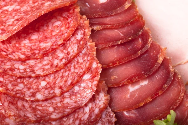 Slices of different types of sausages and salad leaf — Stock Photo, Image