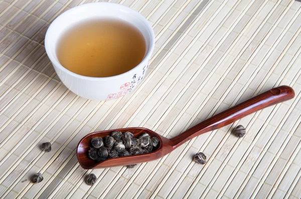 Cup of green tea and tea leaves spoon on a napkin from a bamboo — Stock Photo, Image