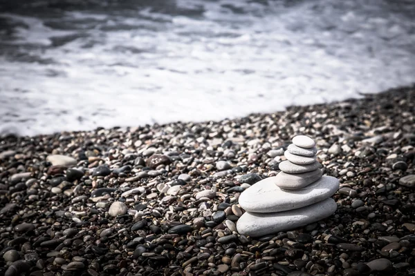 La piramide di ciottoli sulla spiaggia in schiuma di mare — Foto Stock