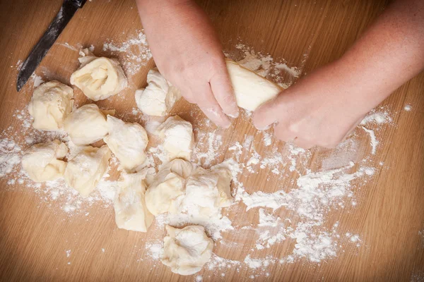 Baker kneads uncooked dough on a wooden table — Stock Photo, Image