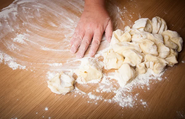 Baker ahşap bir masa üzerinde pişmemiş hamur kneads — Stok fotoğraf