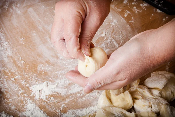 Baker amassa massa de farinha não cozida em uma mesa de madeira — Fotografia de Stock